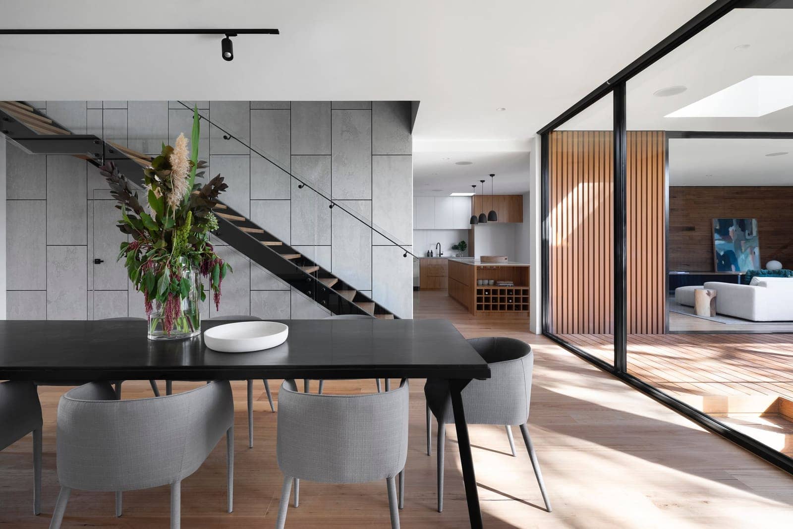 Open-plan living room with a wood accent wall and floating stairs