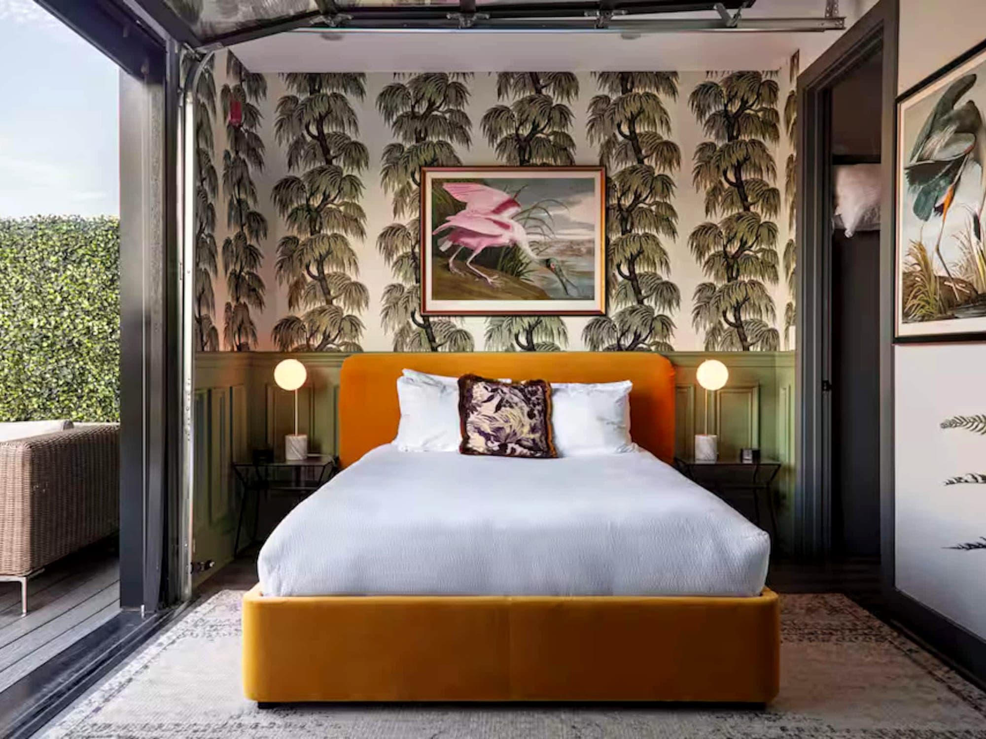 A Boost-managed Nashville studio — palm wallpaper and a mustard velvet bed