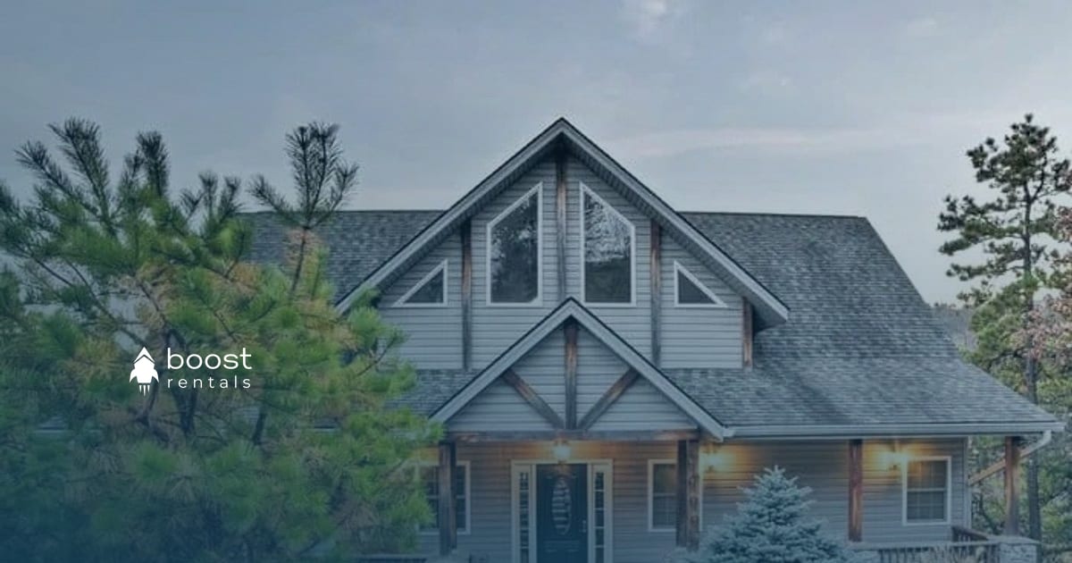 Cabin-style home with a lit porch surrounded by evergreens